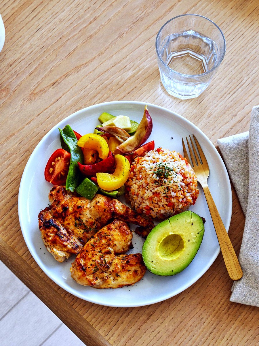 An everyday plate of chicken, roasted vegetables, rice and avocado